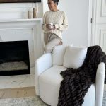 Christine Andrew at home in her primary bedroom with her white accent swivel chair.
