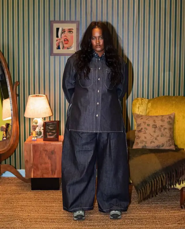 women dressed in streetwear clothing. Consisting of an oversized dark washed denim shirt with matching oversized denim pants.